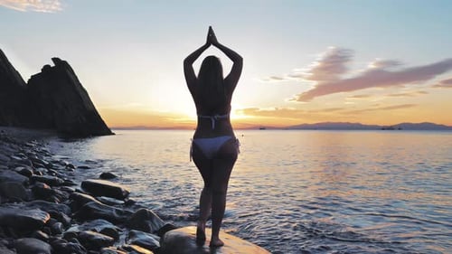 Junge Frau trifft neuen Tag an der Küste Wunderschöner Sonnenaufgangshimmel mit sanftem Sonnenlicht