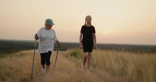 Woman and Teen Walking in Rural Field at Sunset
