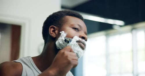 Man Shaving his Face with Razor in Bathroom