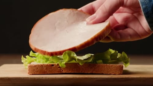 Preparing Sandwich With Lettuce and Meat on Bread