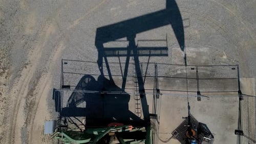 Oil Pumping Jack On Desert Sands In Summer - aerial top down