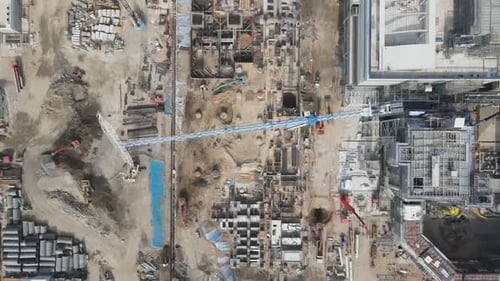 Vista aérea de arriba hacia abajo de un sitio de construcción industrial con dos enormes grúas