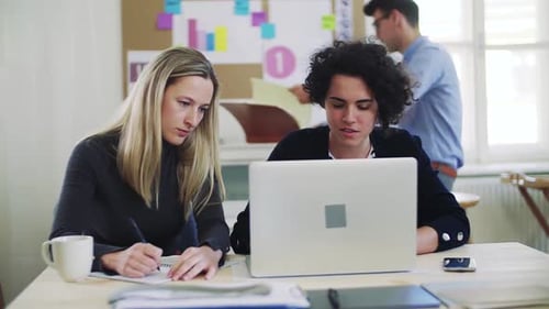 Young business team collaborates on laptop in modern open office space