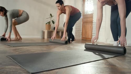 Women Preparing for Yoga Class, Rolling Out Exercise Mats