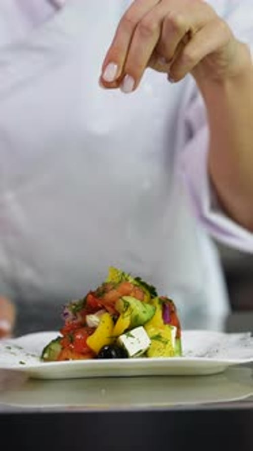 Chef Seasoning Fresh Vegetable Salad in Modern Kitchen