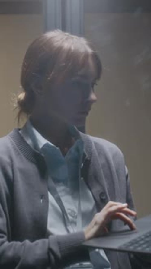 Vertical of Young Professional Female IT Specialist Using Laptop in Data Center