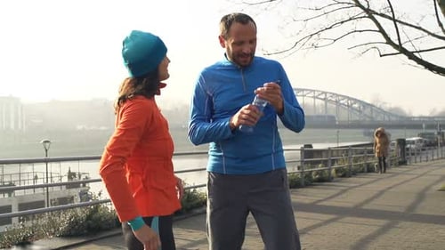 Couple Talking and Drinking Water After Jogging in City 30s