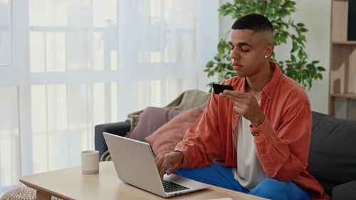 Young Adult Using Laptop and Credit Card Indoors
