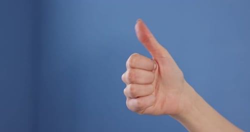 Woman's Hand Giving a Thumbs Up on Blue