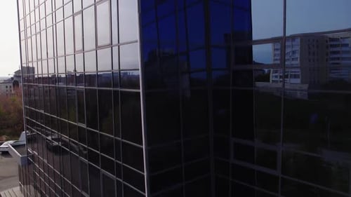 Glass Building Facade Reflecting Sky Against Urban Area Closeup