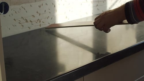 Worker Marking Line on Kitchen Countertop Using Metal Ruler