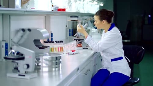 Young Woman Analyzing Samples with Microscope in Lab