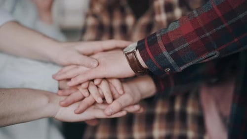Teamwork: Three People Stack Hands in Solidarity