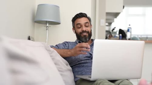 Relaxed Mature Man Using Laptop with Earphones for a Video Call. Cheerful