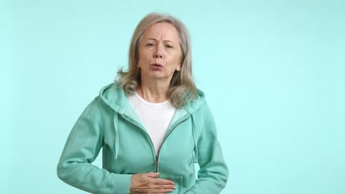 Elderly Woman Feeling Stomach Pain Uncomfortable Ache in Green Hoodie
