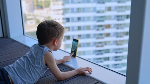 Young Boy Lying Down Using a Mobile Phone