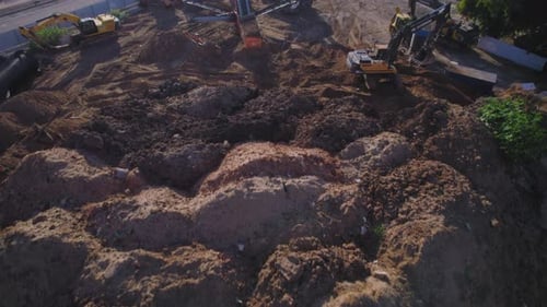 Heavy equipment such as tractors and bulldozers is exposed behind a sand hill