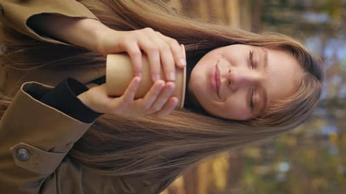 Smiling Woman Holding Coffee Cup Outdoors in Autumn