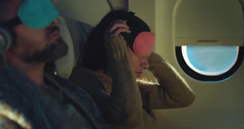 Cinematic shot of young couple putting on sleep masks for napping in air