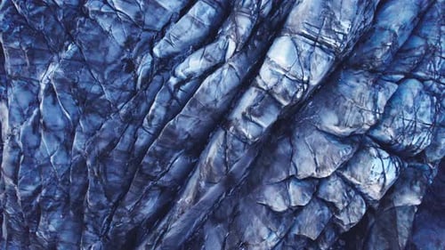 Aerial: descending into Glaciers deep crevasses and jagged ice formations, evidence of the impact cl
