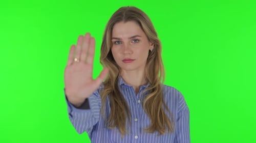 Stop Gesture by Young Woman on Green Background
