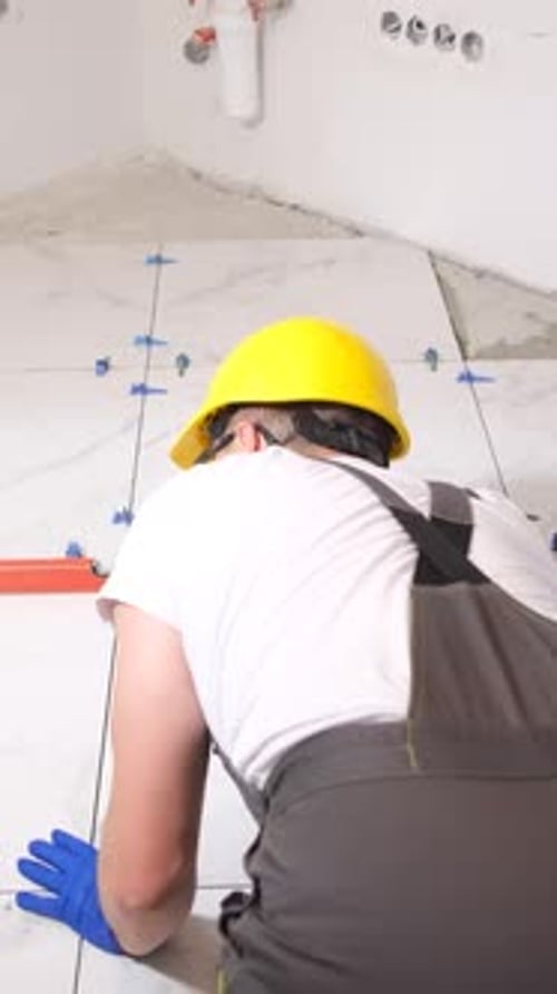 Man Installing White Tiles in Bathroom