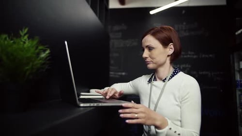 Young businesswoman works on laptop in modern office slow motion