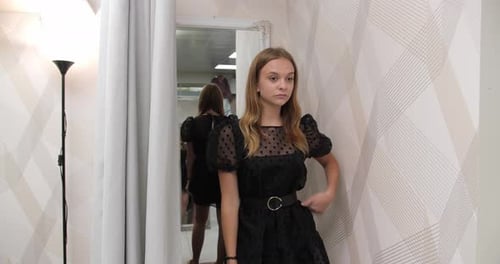 Uma garota experimenta um vestido preto elegante em uma boutique