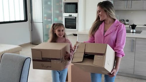 Mutter und Tochter tragen Umzugskartons im neuen Zuhause