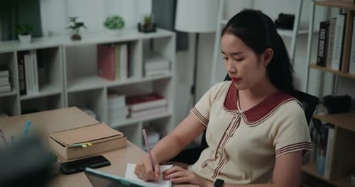 Woman Writing in Notebook at Desk Indoors