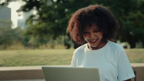 Portrait of Happy African American Woman Freelancer Typing on Laptop in Park