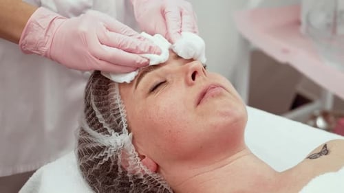 Facial Specialist Cleansing Skin with Cotton Pads Patient Relaxed Skin Therapist Performing Gentle