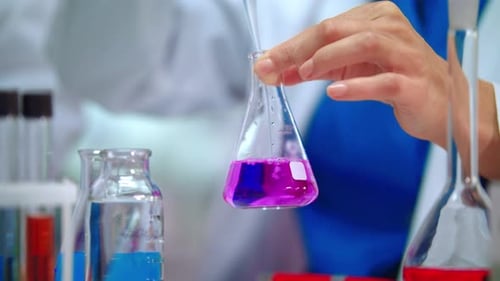 Lab Scientist Pouring Liquid in Lab Flask. Close Up of Female Scientist