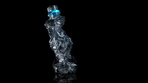 Crushed Plastic Bottle on Black Reflective Surface