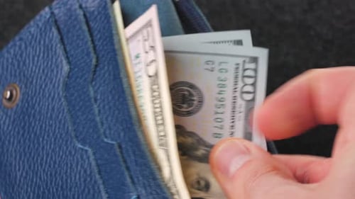 A Closeup View of Cash Being Stored in a Blue Wallet for Financial Purposes