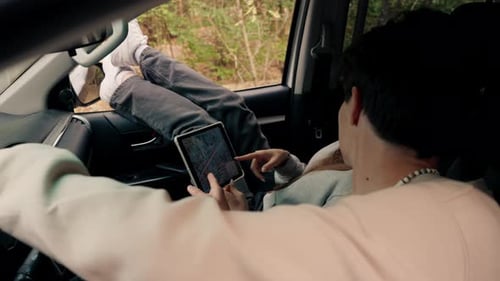 A couple in a car conferring and planning the best route through the forest using map on tablet