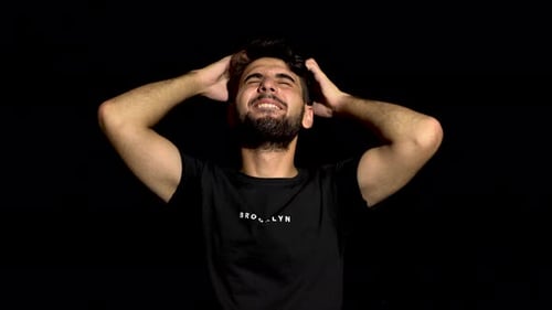 Man Scratching Head on Plain Black Background