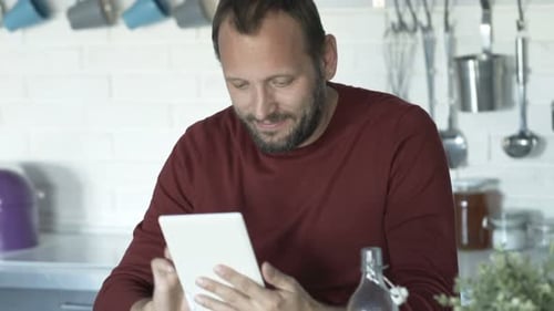 Man Using Tablet in Kitchen at Home
