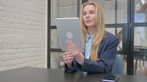 Woman Attends Video Conference on Tablet at Desk
