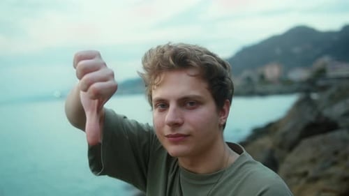 Young blond handsome boy making negative sign with thumb
