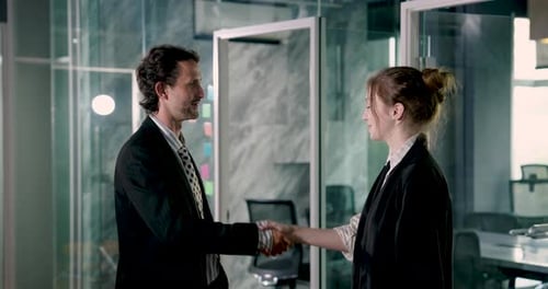 Business colleagues shaking hands with smiles after finalizing agreement in modern office. Confident