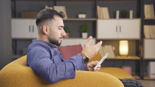 Young Man Video Chatting from Comfortable Chair