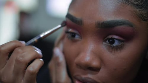 Close-up face of one black latina young woman applies make-up in front of mirror, 20s adult girl of