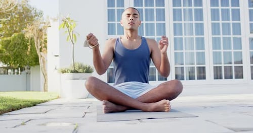 Focused biracial man practicing yoga meditation in sunny garden, slow motion