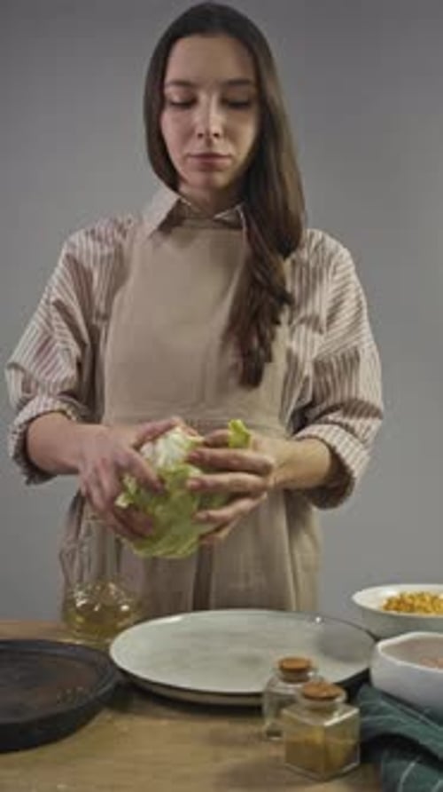 Housewife Wearing an Apron is in Her Kitchen Preparing Salad She is Separating Leaves of Cabbage and