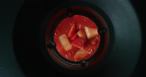 Alternative view of mixing dietetic milkshake with fresh biologic strawberries in slow motion. Sho