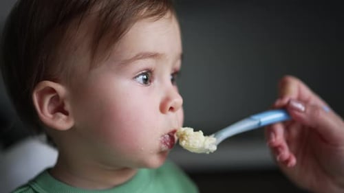 Cute Infant Eating Food with a Spoon