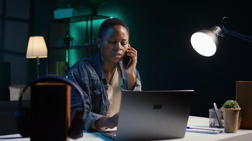 Woman Working at Night on Laptop Answering Phone