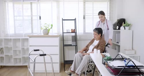 Doctor Pushing Senior Woman in Wheelchair Indoors