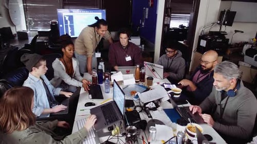 Team Collaborates at Table with Laptops in Office